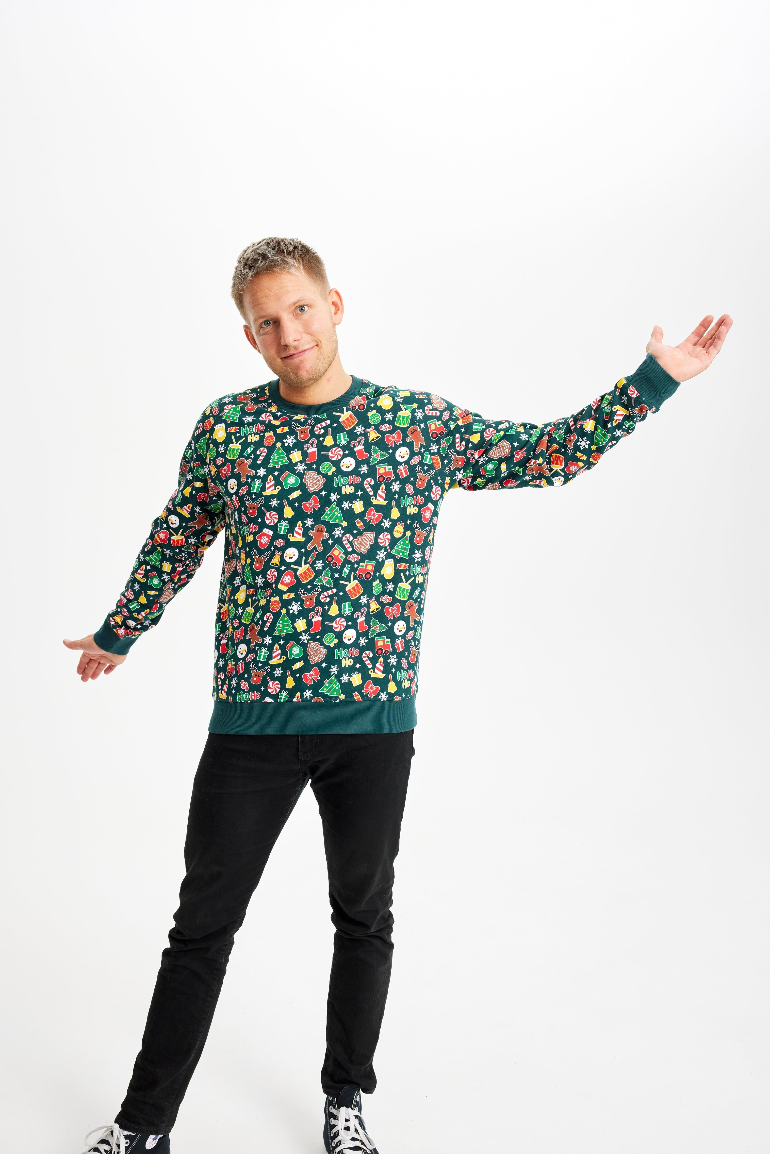 Een man draagt een groene kersttrui met een kerstpatroon.